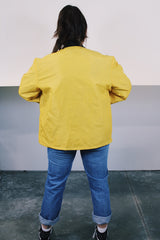 Women's or men's vintage 1970's long sleeve yellow nylon zip up bomber jacket with black knit trim and black graphic on left chest.