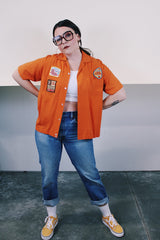 Men's vintage 1960's Joel's Striker short sleeve orange button up bowling shirt with three patches sewn on. Rayon acrylic blend material. One chest pocket and small collar.