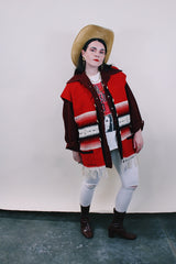 Women's or men's vintage boho western style 1970's sleeveless red wool vest with black trim, cream fringe trim on hem, and black and cream stripes.