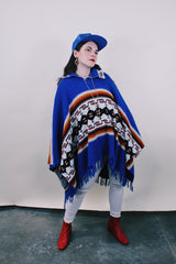 Women's or men's vintage 1970's blue acrylic material poncho with fringe trim and half zipper closure at neck. White. black, brown, and red striped print.
