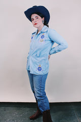 Women's or men's vintage 1970's long sleeve light wash denim shirt with popper buttons, pockets, belt loops, and floral embroidery throughout.