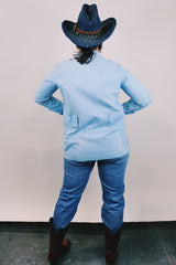 Women's or men's vintage 1970's long sleeve light wash denim shirt with popper buttons, pockets, belt loops, and floral embroidery throughout.