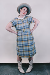 Women's vintage western style 1960's short sleeve midi length plaid print shift dress with white scalloped trim. Grey, teal, and mustard yellow colors.