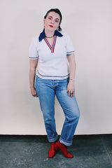 Women's or men's vintage 1970's short sleeve white top with navy collar, two button half closure in a nubby textured stretchy polyester material.