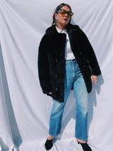 black faux fur coat with collar and buttons up the front and leather panels under the arms and on the side