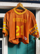 short sleeve burnt orange cropped football jersey with yellow stripes, wording, and trim vintage 1970's