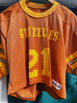 short sleeve burnt orange cropped football jersey with yellow stripes, wording, and trim vintage 1970's