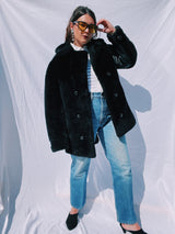 black faux fur coat with collar and buttons up the front and leather panels under the arms and on the side