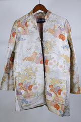 Women's vintage 1960's long sleeve and long length gold colored silk robe kimono with all over multicolored embroidered floral design. Pockets, mandarin collar and fabric covered buttons