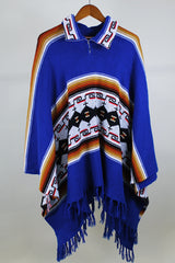 Women's or men's vintage 1970's blue acrylic material poncho with fringe trim and half zipper closure at neck. White. black, brown, and red striped print.