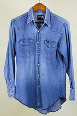 Women's or men's vintage 1980's Wrangler, Preshrunk, X-Long Tails, Made in USA label long sleeve medium wash denim Wrangler western style button up shirt with pearl popper buttons.