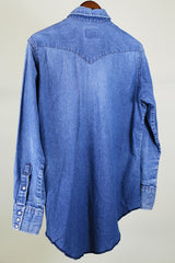 Women's or men's vintage 1980's Wrangler, Preshrunk, X-Long Tails, Made in USA label long sleeve medium wash denim Wrangler western style button up shirt with pearl popper buttons.