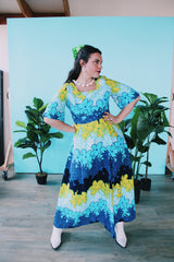 Women's vintage 1970's Sears Hawaiian Fashions label short sleeve maxi length cotton material Hawaiian print dress in green, blue, and white print with a square neckline.