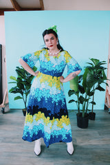 Women's vintage 1970's Sears Hawaiian Fashions label short sleeve maxi length cotton material Hawaiian print dress in green, blue, and white print with a square neckline.