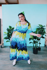 Women's vintage 1970's Sears Hawaiian Fashions label short sleeve maxi length cotton material Hawaiian print dress in green, blue, and white print with a square neckline.