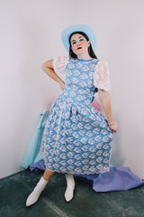 Women's vintage 1980's blue polyester dress with a white lace overlay. Has sheer puff sleeves, side zipper, low cut back, and a lace bow in the back