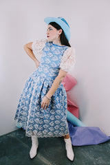 Women's vintage 1980's blue polyester dress with a white lace overlay. Has sheer puff sleeves, side zipper, low cut back, and a lace bow in the back
