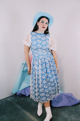 Women's vintage 1980's blue polyester dress with a white lace overlay. Has sheer puff sleeves, side zipper, low cut back, and a lace bow in the back