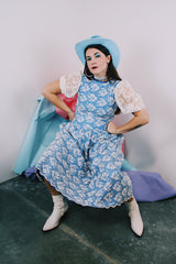 Women's vintage 1980's blue polyester dress with a white lace overlay. Has sheer puff sleeves, side zipper, low cut back, and a lace bow in the back