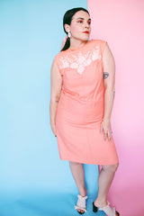 Women's vintage 1960's midi length sleeveless peach orange colored shirt dress with white beads across chest creating a floral print.