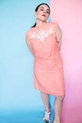 Women's vintage 1960's midi length sleeveless peach orange colored shirt dress with white beads across chest creating a floral print.