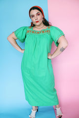 Women's vintage 1970's short sleeve cotton material green short sleeve ankle length dress with orange embroidery and a square neckline and puff sleeves.