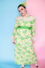 Women's vintage 1970's long sleeve maxi length floral print dress in green and white colors. Sheer white ruffle trim, ribbon belt.
