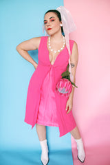 Women's vintage 1960's sleeveless mini length babydoll dress in bright pink with V shaped neckline and bow on chest.