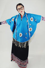 blue wool poncho with white embroidered flowers and white fringe on hem vintage