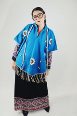 blue wool poncho with white embroidered flowers and white fringe on hem vintage