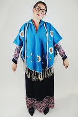 blue wool poncho with white embroidered flowers and white fringe on hem vintage