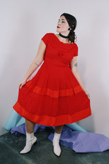 Women's vintage 1960's short sleeve capped sleeve knee length midi dress in vibrant red with a scoop neckline and flower on chest.