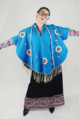 blue wool poncho with white embroidered flowers and white fringe on hem vintage
