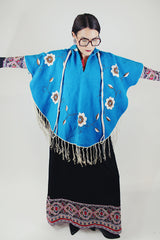 blue wool poncho with white embroidered flowers and white fringe on hem vintage