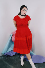 Women's vintage 1960's short sleeve capped sleeve knee length midi dress in vibrant red with a scoop neckline and flower on chest.