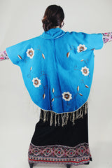blue wool poncho with white embroidered flowers and white fringe on hem vintage