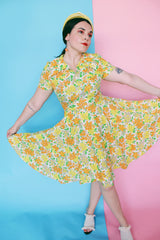 Women's vintage 1960's short sleeve polyester material mini length dress with all over green, orange, and yellow floral print.