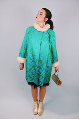 green statin long sleeve knee length jacket with floral pattern and cream faux fur trim around cuffs and neck vintage 1960's