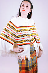 white vintage women's 1960's acrylic knit poncho with striped pattern and fringed hem