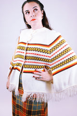 white vintage women's 1960's acrylic knit poncho with striped pattern and fringed hem