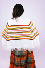white vintage women's 1960's acrylic knit poncho with striped pattern and fringed hem