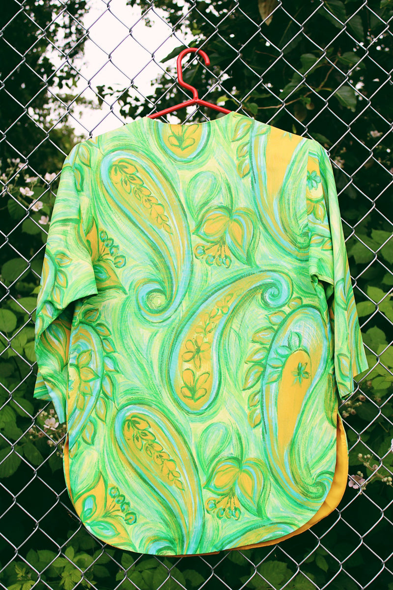 Women's vintage 1970's Alex Colman California label 3/4 arm length button up smock blouse in a vibrant green abstract print. Brass buttons and side slits. 