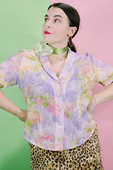 Women's vintage 1980's R&K Originals label short sleeve sheer button up blouse with all over purple and pink floral print with a slit in the back.