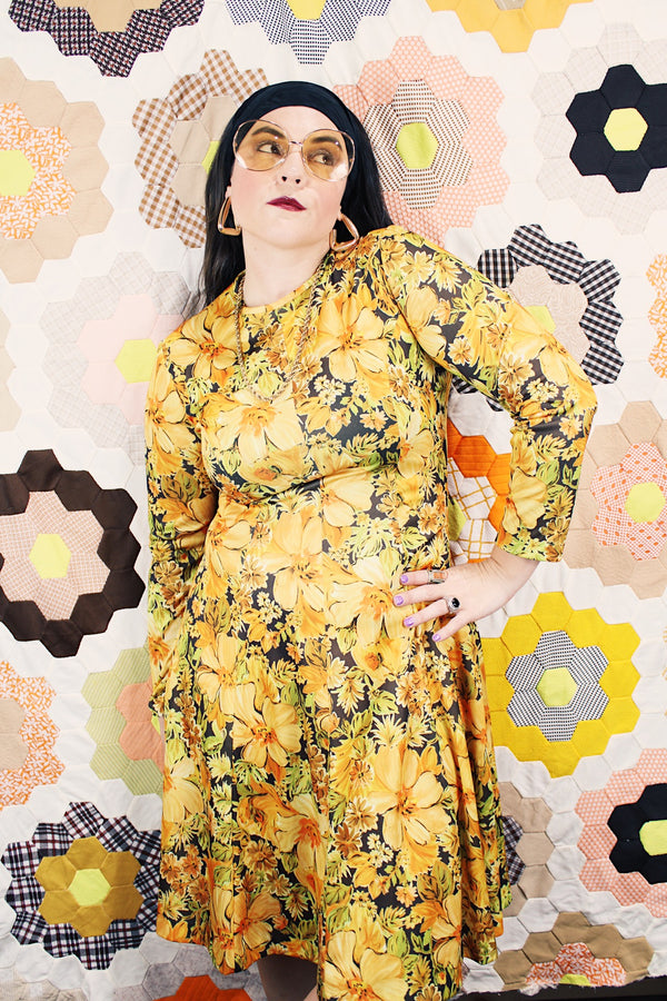 Women's vintage 1970's long sleeve knee length dress in a lightweight polyester material. All over yellow and orange floral print.