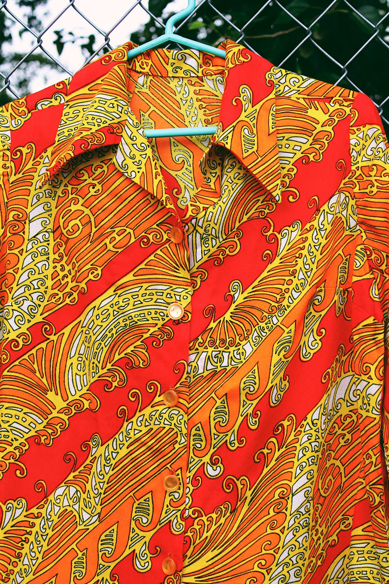 Women's vintage 1970's long sleeve button up blouse with dagger collar in an all over red, orange, and yellow vibrant abstract print.