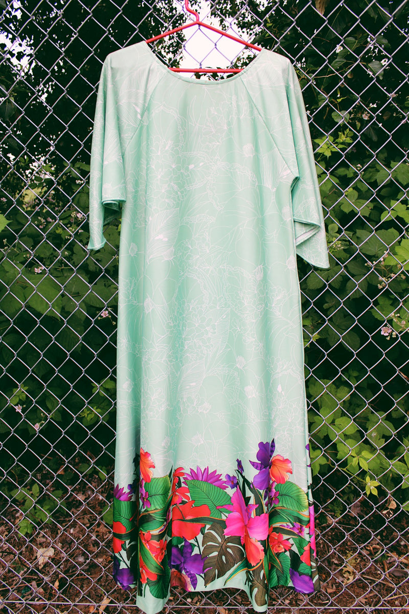 Women's vintage 1970's Butterfield 8, Made in USA label bell sleeved maxi length dress in light pastel green with Hawaiian floral print on the hem. 