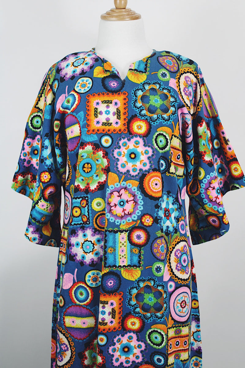 Women's vintage 1970's cotton material short sleeve maxi length dress with all over multicolored print. Has big flared sleeves and a V shaped neckline.