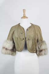 Women's vintage 1970's cropped fit tan suede jacket with short sleeves and two snap button closure in the front. Sleeves have a cream fur trim.