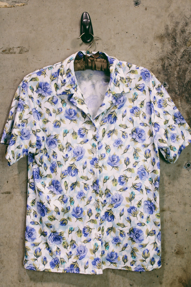 Women's vintage 1980's LORI by AM Casuals short sleeve button up blouse in white with all over blue floral print. Stretchy polyester material. 