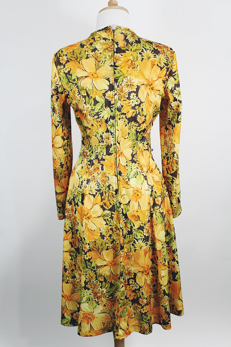Women's vintage 1970's long sleeve knee length dress in a lightweight polyester material. All over yellow and orange floral print.